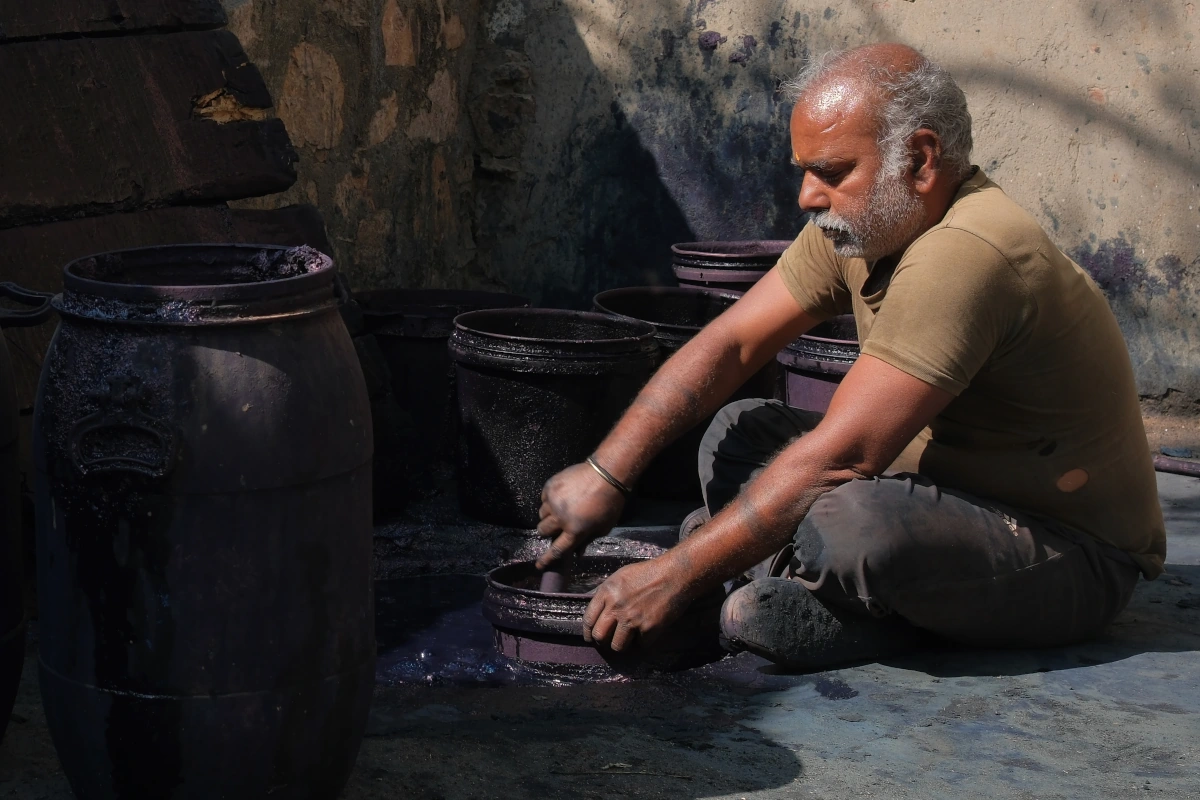Artisan rajasthani créant une teinture indigo naturelle pour impression blockprint dans un village traditionnel. 