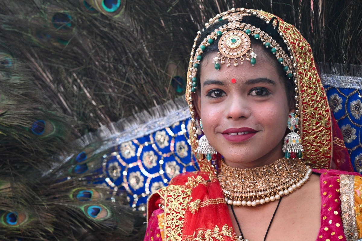 Young girl in traditional costume with peacock feathers at the Pushkar Camel Fair, Rajasthan, India.